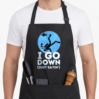 Sayin snorkeling apron - Cartoon diver in blue circle above I GO DOWN JUST SAYIN text — shown on a black cotton canvas apron against a white background