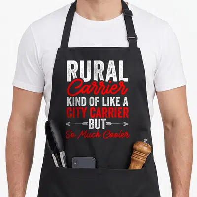 Postman rural apron - Stacked white and red text reading Rural Carrier Kind Of Like A City Carrier But So Much Cooler — shown on a black cotton canvas apron against a white background