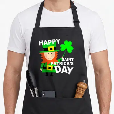 Toddler st patrick day aprons - Cartoon leprechaun holding green shamrock with white Happy Saint Patrick's Day text — shown on a black cotton canvas apron against a white background