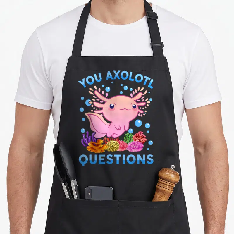 Axolotl question anime apron - Pink cartoon axolotl with blue text and colorful coral bubbles — shown on a black cotton canvas apron against a white background