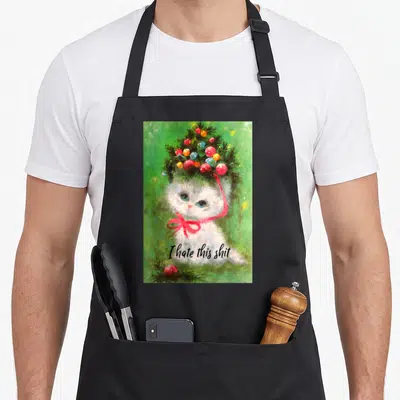 Kitsch crazy cat lady apron - Watercolor kitten with Christmas tree hat and 'I hate this shit' text on black apron — shown on a black cotton canvas apron against a white background