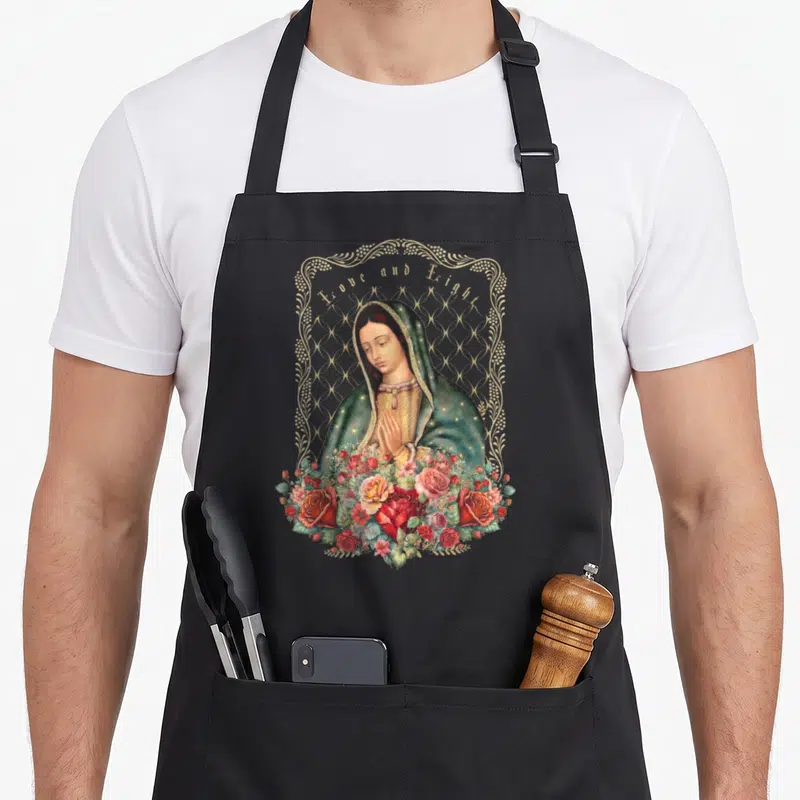 Funny saint catholic apron - Virgin Mary with clasped hands inside gold frame, surrounded by red and pink roses, arched — shown on a black cotton canvas apron against a white background