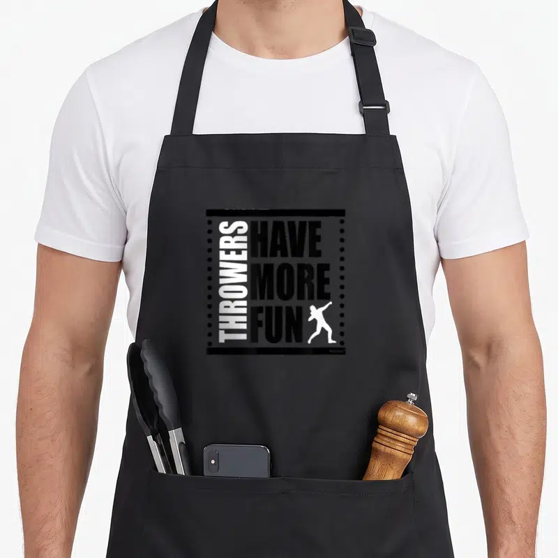 Field shot track apron - Black and white block text reading Throwers Have More Fun with athlete silhouette and dotted — shown on a black cotton canvas apron against a white background