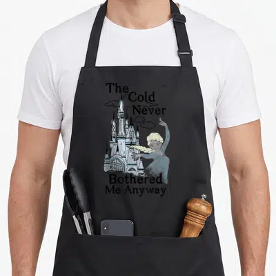 Cold best class ever apron - Elsa and castle illustration with text The Cold Never Bothered Me Anyway — shown on a black cotton canvas apron against a white background