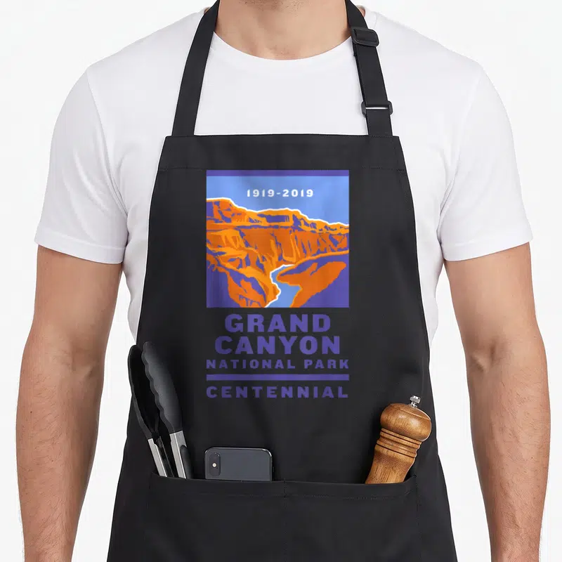 National grand canyon apron - 1919-2019 GRAND CANYON NATIONAL PARK CENTENNIAL text with purple orange blue canyon — shown on a black cotton canvas apron against a white background