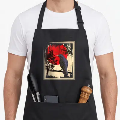 Moon crow gothic apron - Retro crow on branch before red sun with black trees and beige border — shown on a black cotton canvas apron against a white background