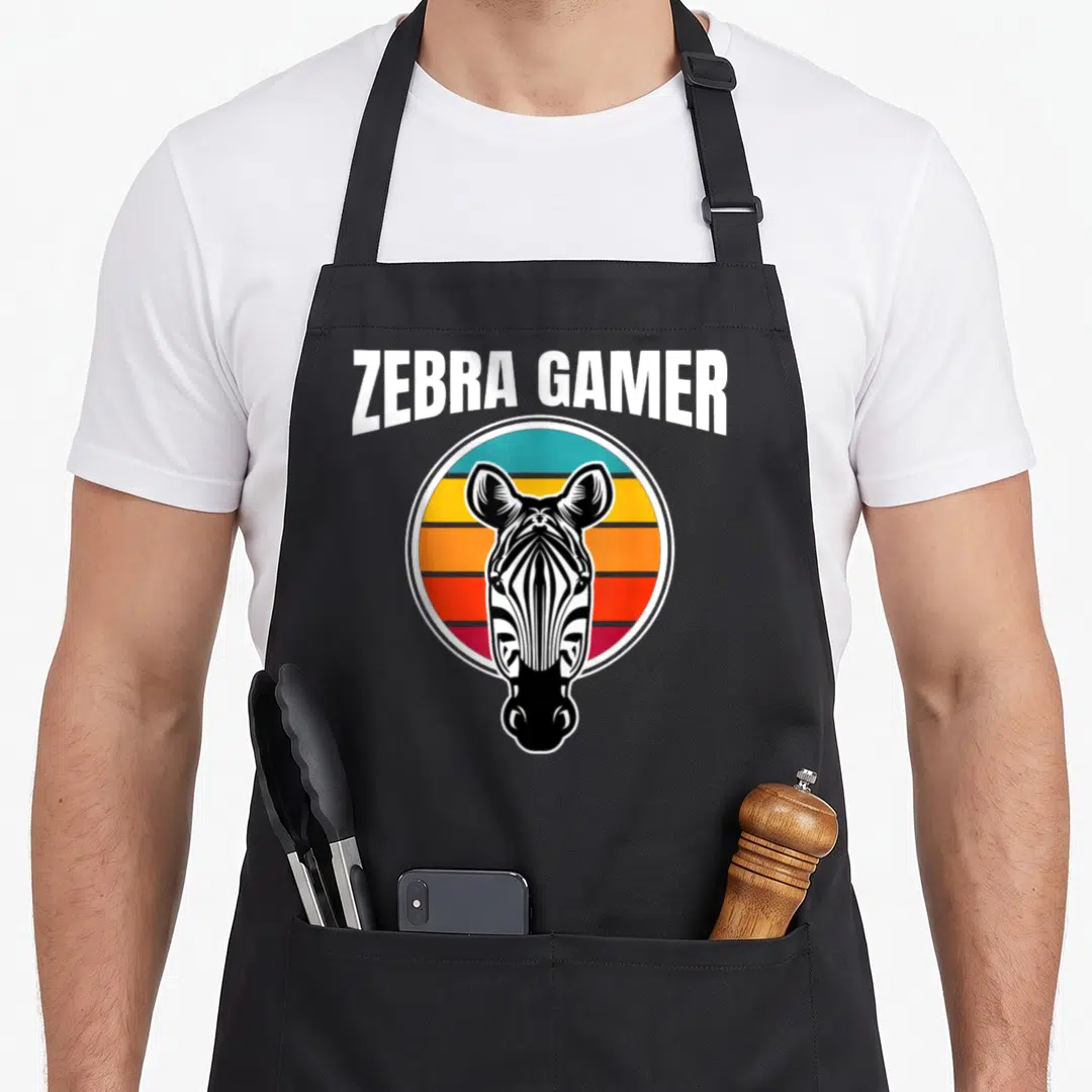 Funny gamer zebra apron - Arched ZEBRA GAMER text above zebra head inside retro sunset circle — shown on a black cotton canvas apron against a white background