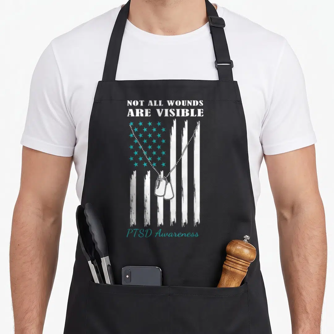 Flag ptsd awareness apron - Distressed USA flag with teal stars, two dog tags, and PTSD Awareness text — shown on a black cotton canvas apron against a white background