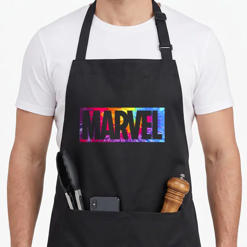 Box tie apron - MARVEL text in grey over red yellow blue purple tie-dye rectangle — shown on a black cotton canvas apron against a white background