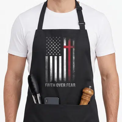 Christian cross apron - Distressed US flag with red cross and Faith Over Fear text — shown on a black cotton canvas apron against a white background