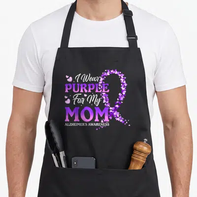 Retro dementia alzheimer's aprons - I Wear PURPLE For My MOM text with purple white pink heart ribbon — shown on a black cotton canvas apron against a white background