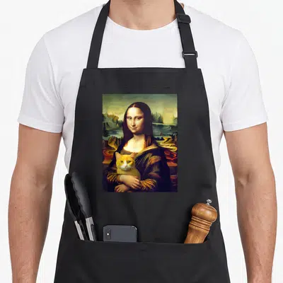 Leonardo cat holding apron - Mona Lisa figure holding orange and white cat against green landscape — shown on a black cotton canvas apron against a white background