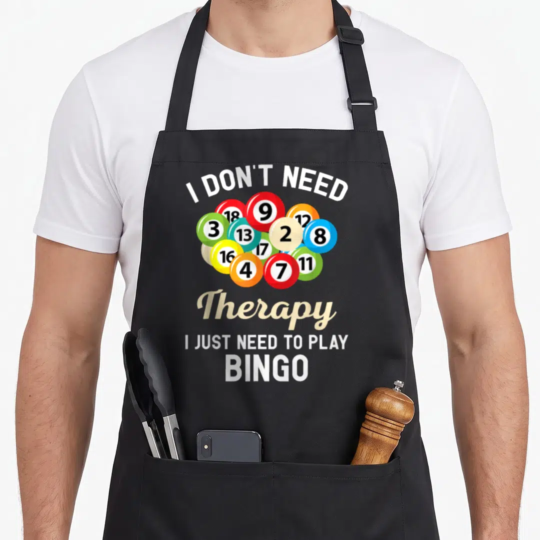 Game player bingo aprons - Stacked text I DON'T NEED Therapy I JUST NEED TO PLAY BINGO with colorful numbered balls — shown on a black cotton canvas apron against a white background