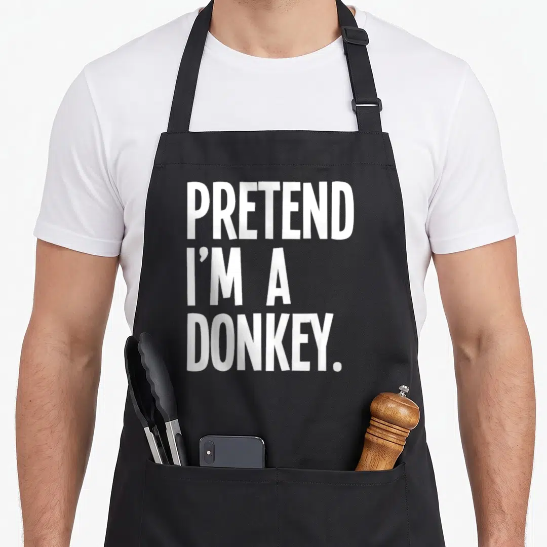 Donkey cute halloween aprons - White stacked text reading Pretend I'm A Donkey on dark background — shown on a black cotton canvas apron against a white background