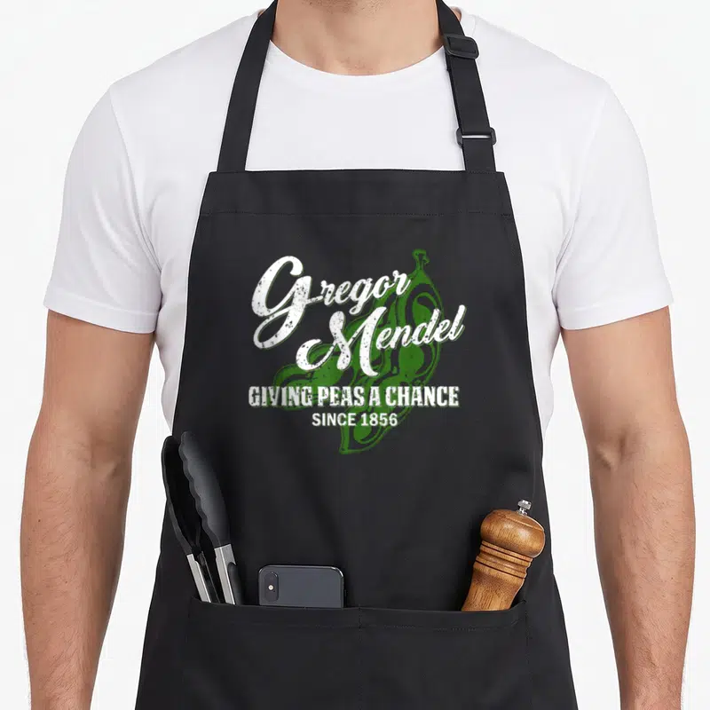 Mendel biology apron - Green pea pod with distressed white text reading Gregor Mendel giving peas a chance since 1856 — shown on a black cotton canvas apron against a white background