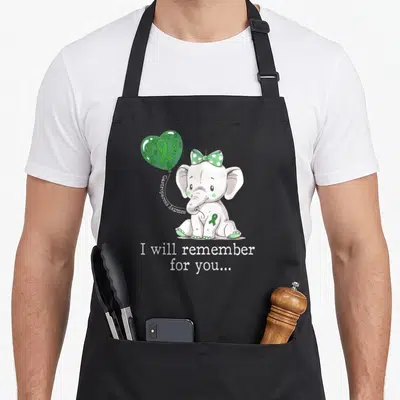 Elephant gastroparesis awareness apron - Cartoon elephant with green bow holding a heart balloon printed with awareness — shown on a black cotton canvas apron against a white background