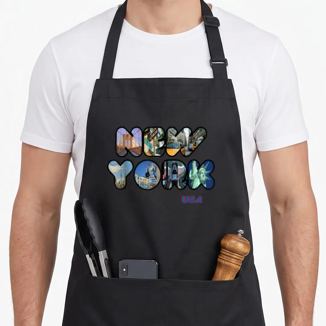 Statue liberty new york apron - NEW YORK letters filled with city photos and red USA text below — shown on a black cotton canvas apron against a white background