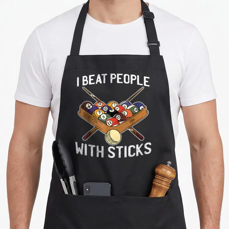 Beat billiards lover apron - I BEAT PEOPLE WITH STICKS text over rack of billiard balls and crossed cues — shown on a black cotton canvas apron against a white background
