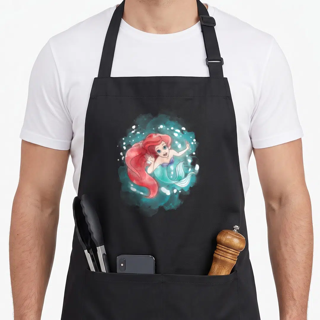 Cute ariel mermaid apron - Mermaid with red hair in teal watercolor splash with white bubbles — shown on a black cotton canvas apron against a white background