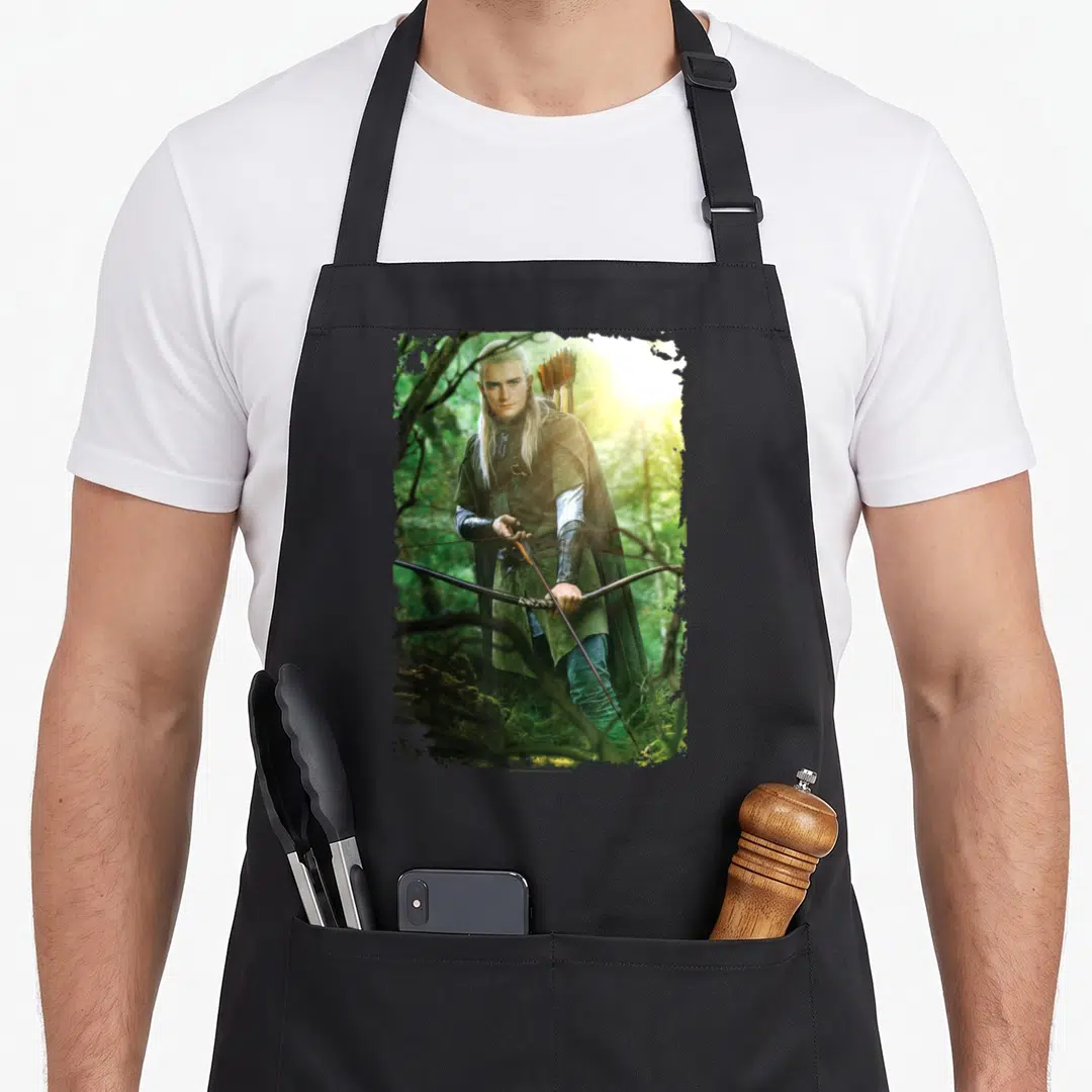 Legolas ring apron - Photo of elf archer with bow in ragged frame against forest background in green and brown tones — shown on a black cotton canvas apron against a white background