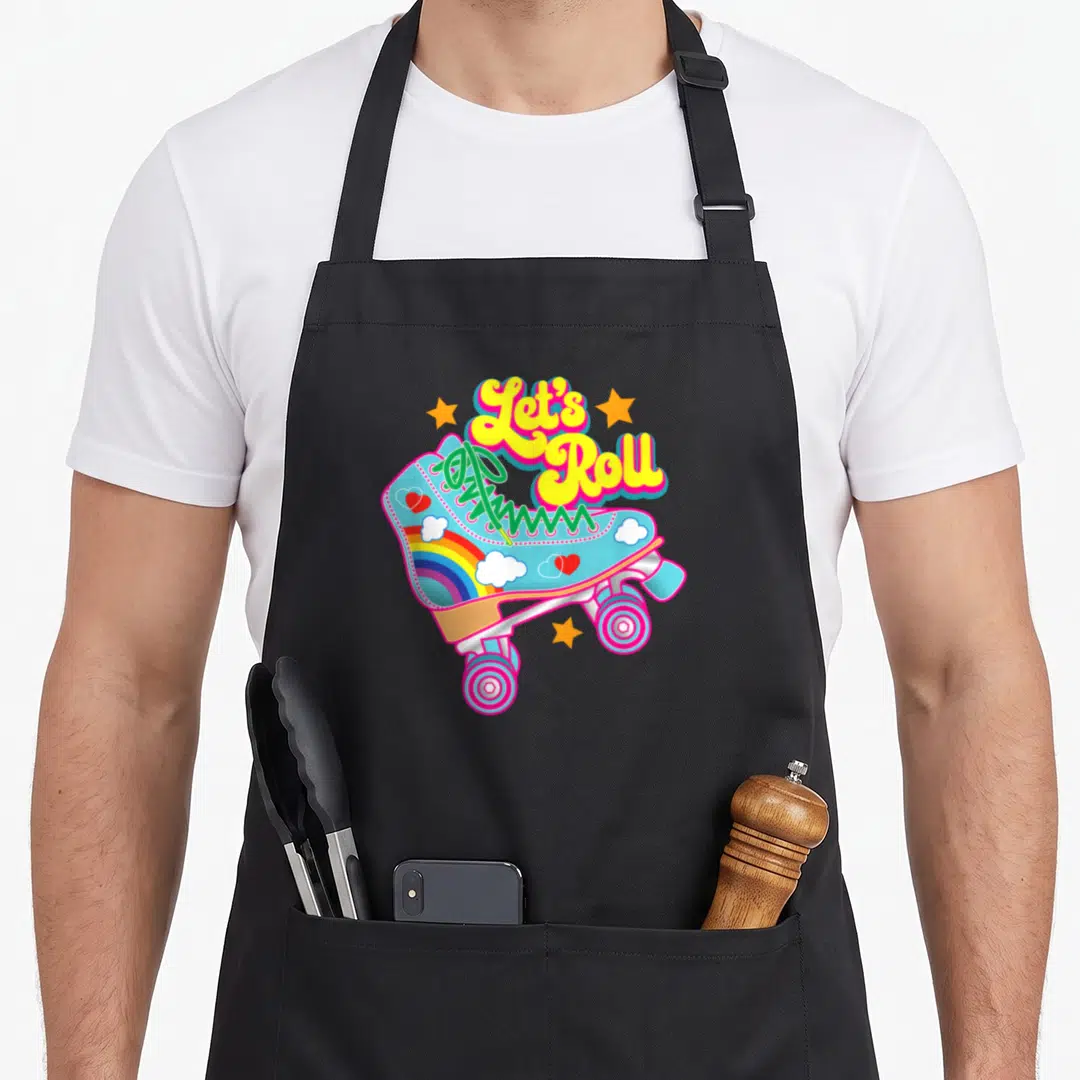 Rollerskating 70s apron - Arched Let's Roll text above light blue skate with rainbow, clouds, hearts, and three orange — shown on a black cotton canvas apron against a white background