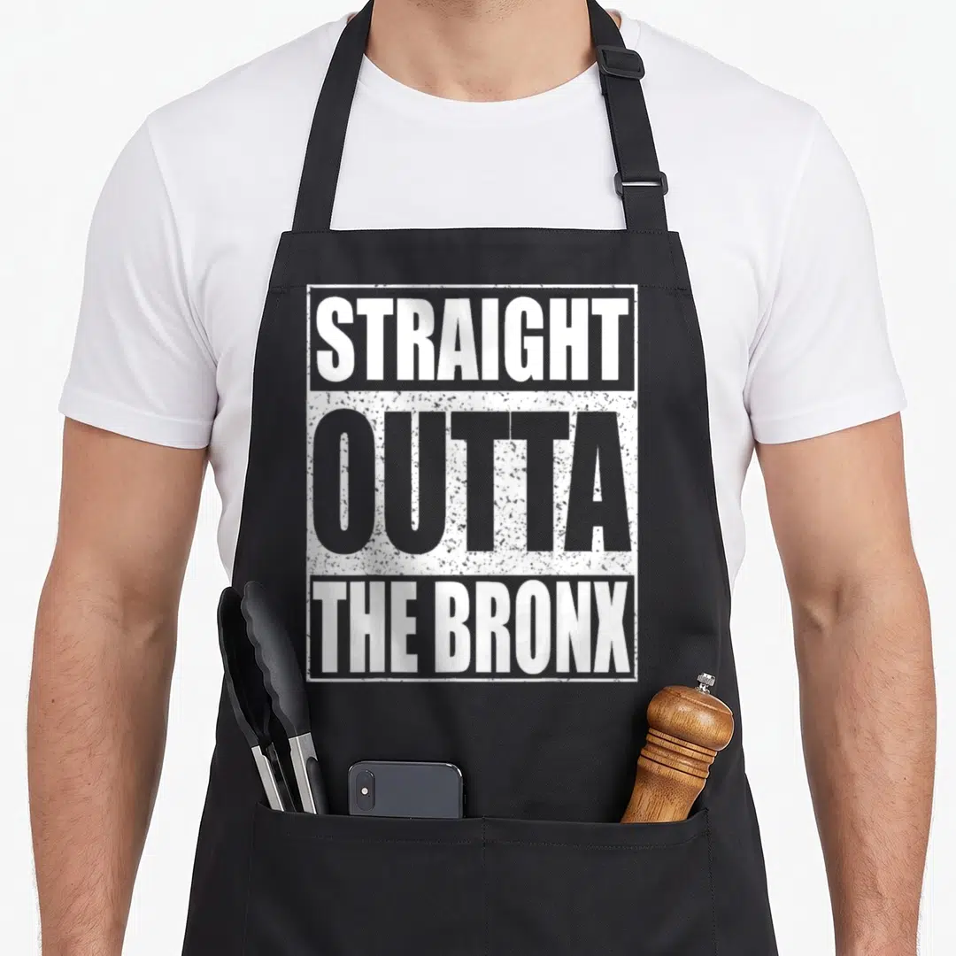 Straight new york apron - STRAGHT OUTTA THE BRONX stacked white and grey typography inside rectangular border — shown on a black cotton canvas apron against a white background