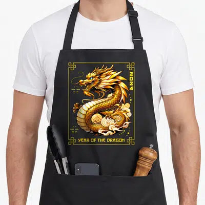Chinese lunar dragon apron - Coiled gold dragon with white clouds, 2024 text, and YEAR OF THE DRAGON in yellow border — shown on a black cotton canvas apron against a white background