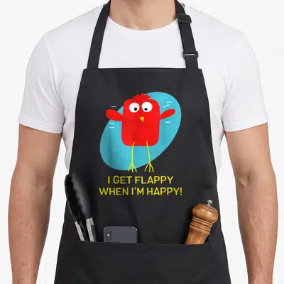 Flappy clean girl apron - Red bird on blue oval with yellow text I GET FLAPPY WHEN I'M HAPPY — shown on a black cotton canvas apron against a white background