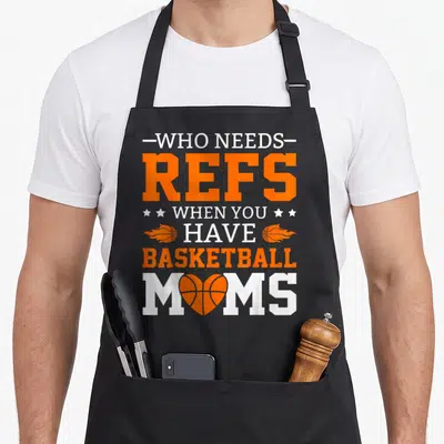 Ref bassinet apron - Stacked Who Needs Refs Basketball Moms text with flaming balls and heart shaped ball — shown on a black cotton canvas apron against a white background