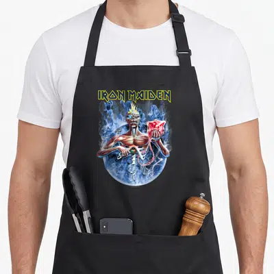 7th dad and son aprons - Realistic zombie holding a red brain under yellow and blue IRON MAIDEN text — shown on a black cotton canvas apron against a white background