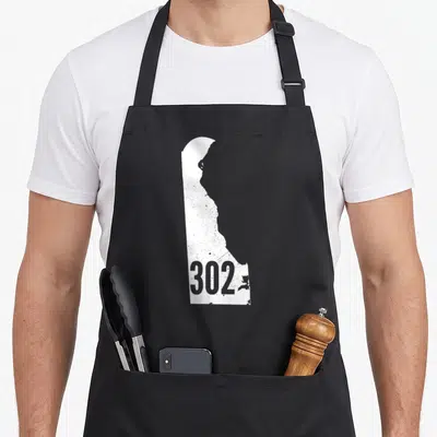 Delaware outline of an apron - White Delaware state map silhouette with grey 302 area code text inside — shown on a black cotton canvas apron against a white background