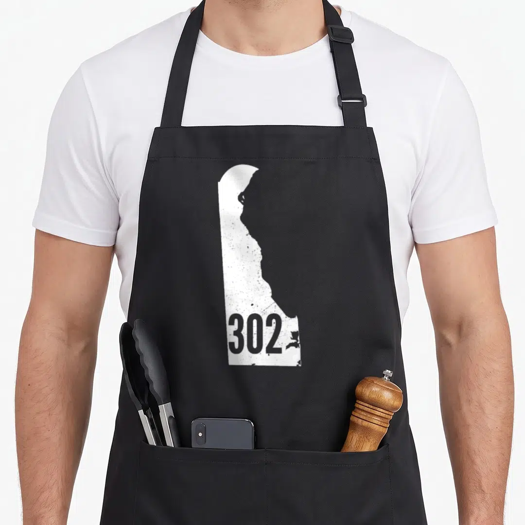 Delaware outline of an apron - White Delaware state map silhouette with grey 302 area code text inside — shown on a black cotton canvas apron against a white background