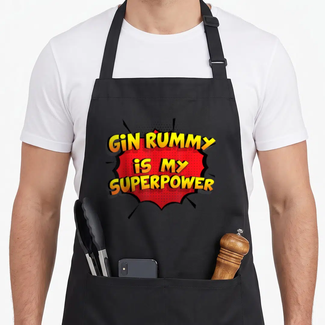 Rummy funny gin apron - Red comic burst with yellow text GIN RUMMY is MY SUPERPOWER — shown on a black cotton canvas apron against a white background