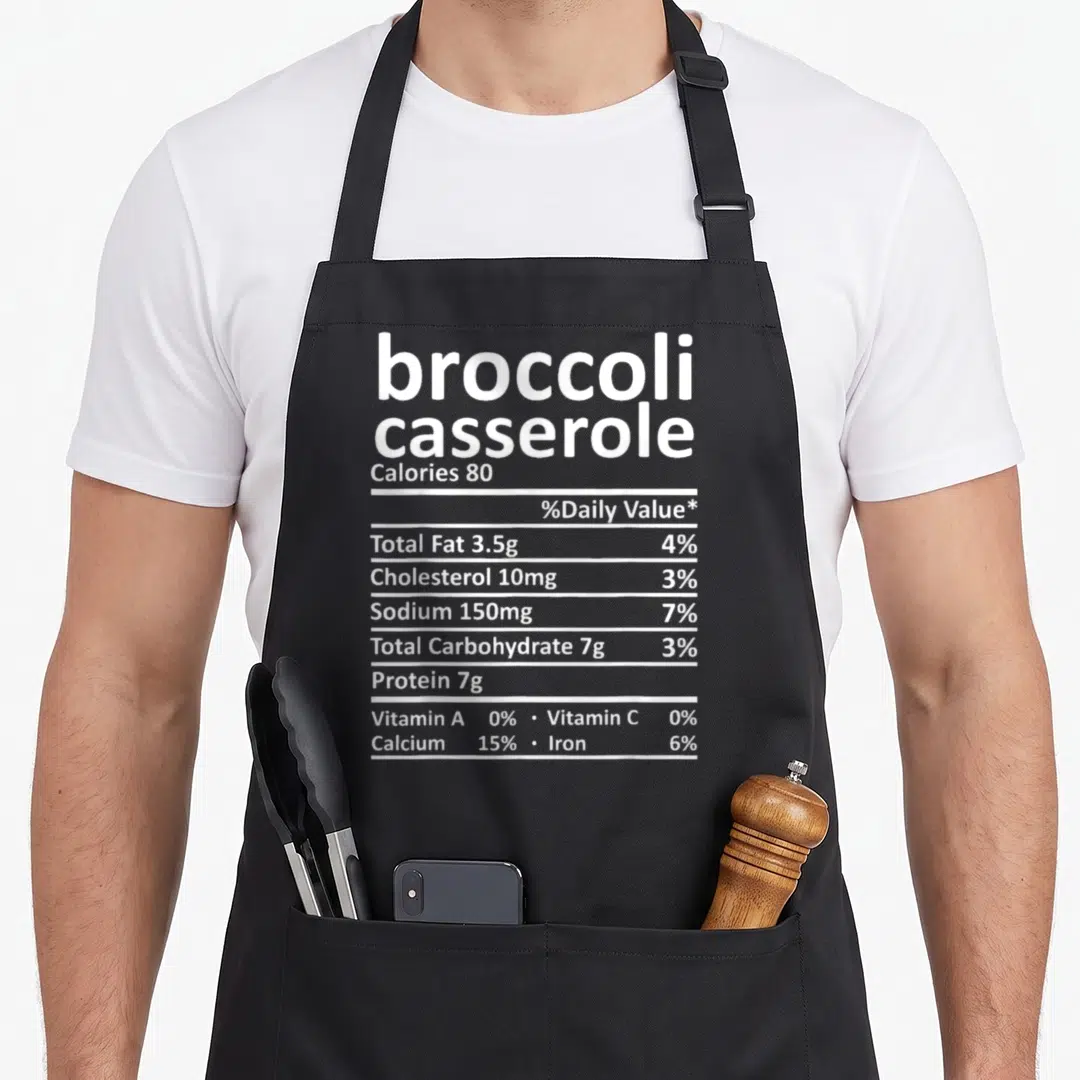 Broccoli xmas apron - White nutrition facts label text listing broccoli casserole calories and nutrients — shown on a black cotton canvas apron against a white background