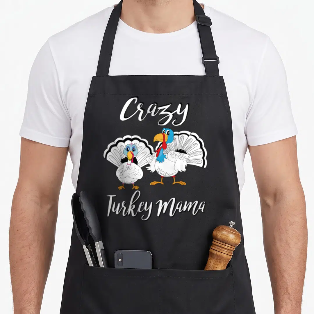 Mama thanksgiving apron - Two cartoon turkeys with Crazy Turkey Mama text in white script — shown on a black cotton canvas apron against a white background