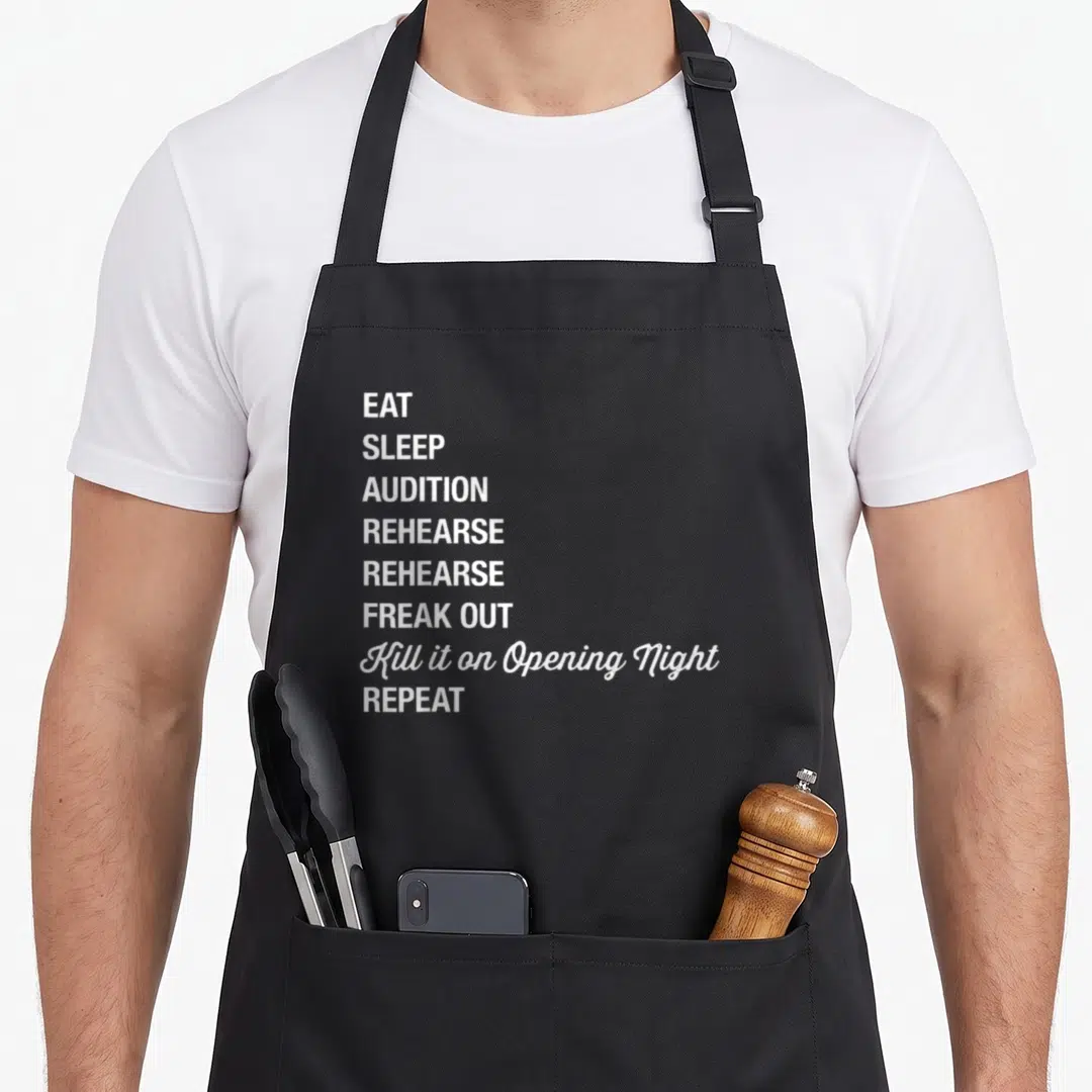 Geek theatre apron - White stacked text reading EAT SLEEP AUDITION REHEARSE FREAK OUT Kill it on Opening Night REPEAT — shown on a black cotton canvas apron against a white background