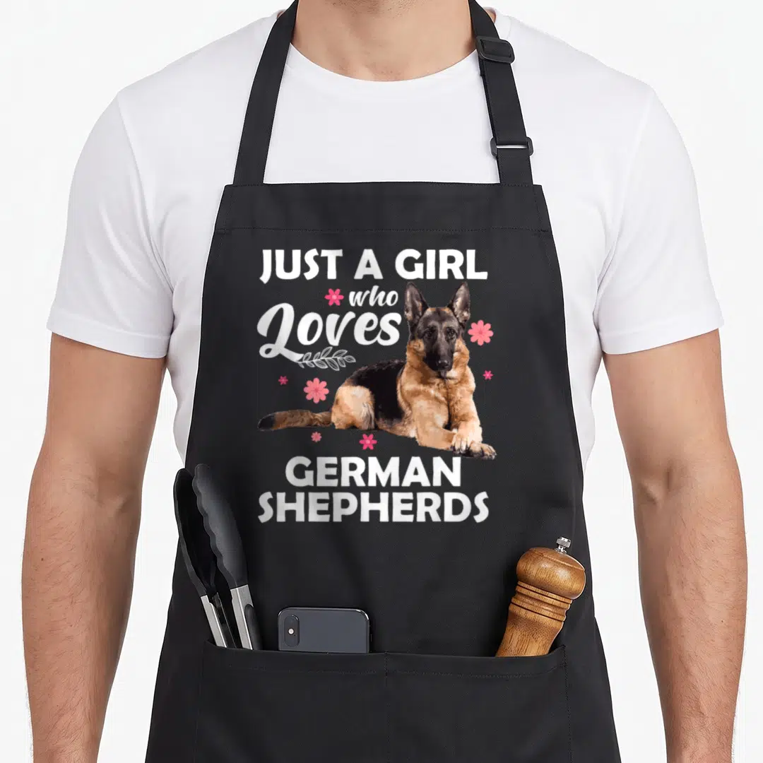 Funny german dog mom apron - Just a girl who loves German Shepherds text surrounding a black and tan dog with pink — shown on a black cotton canvas apron against a white background