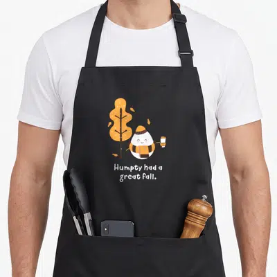 Humpty autumn cute fall aprons - Cartoon egg in scarf holding coffee near orange tree with text Humpty had a great fall — shown on a black cotton canvas apron against a white background