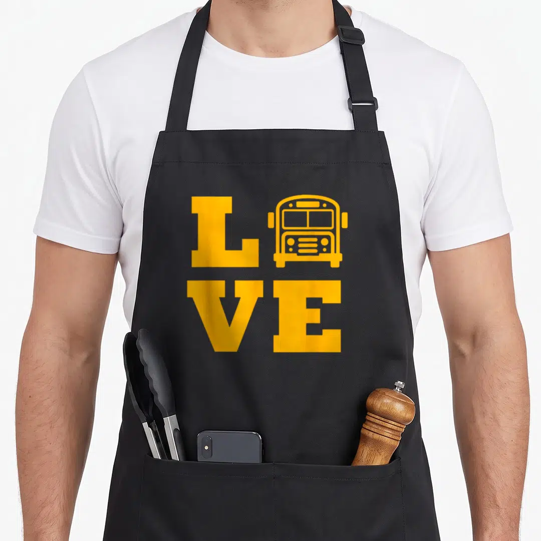 Buse omnibus apron - Yellow square grid spelling LOVE with a school bus icon replacing the letter O — shown on a black cotton canvas apron against a white background