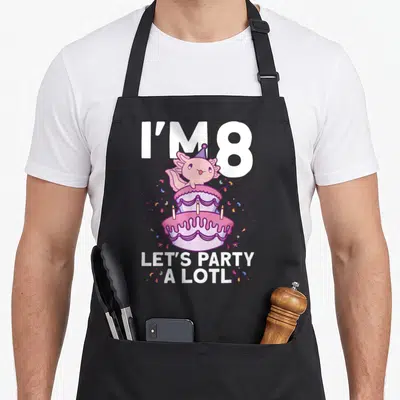 Axolotl bday birthday apron - Pink axolotl on two-tier cake with party text and confetti — shown on a black cotton canvas apron against a white background