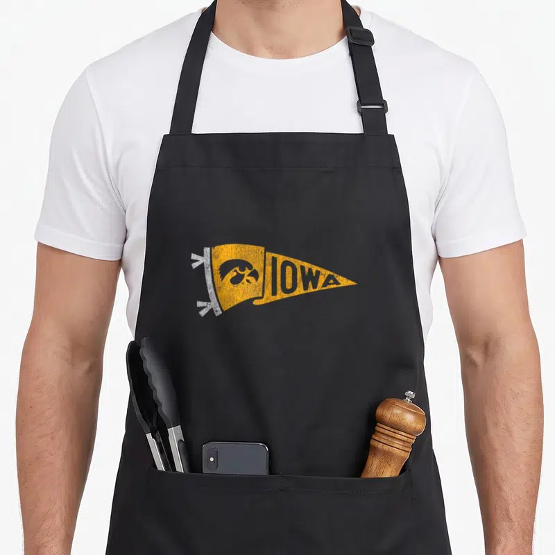Pennant iowa hawkeyes apron - Distressed yellow pennant with IOWA text and hawk head on black apron — shown on a black cotton canvas apron against a white background