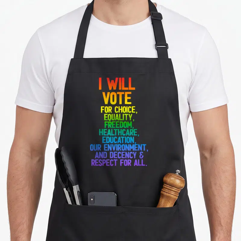 Vote education apron - Rainbow stacked text reading I Will Vote for Choice Equality Freedom Healthcare Education — shown on a black cotton canvas apron against a white background