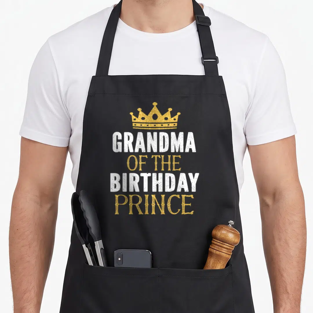 Prince grandma apron - Gold crown above white and gold text reading GRANDMA OF THE BIRTHDAY PRINCE — shown on a black cotton canvas apron against a white background