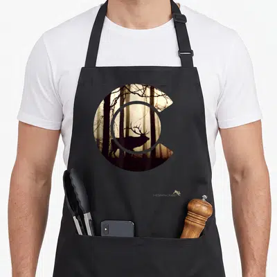 Elk colorado apron - Minimalist deer silhouette and trees inside a C shape with black brown grey beige tones — shown on a black cotton canvas apron against a white background