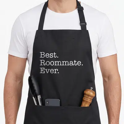 Roommate apron for men - White distressed text reading Best Roommate Ever stacked in three lines — shown on a black cotton canvas apron against a white background