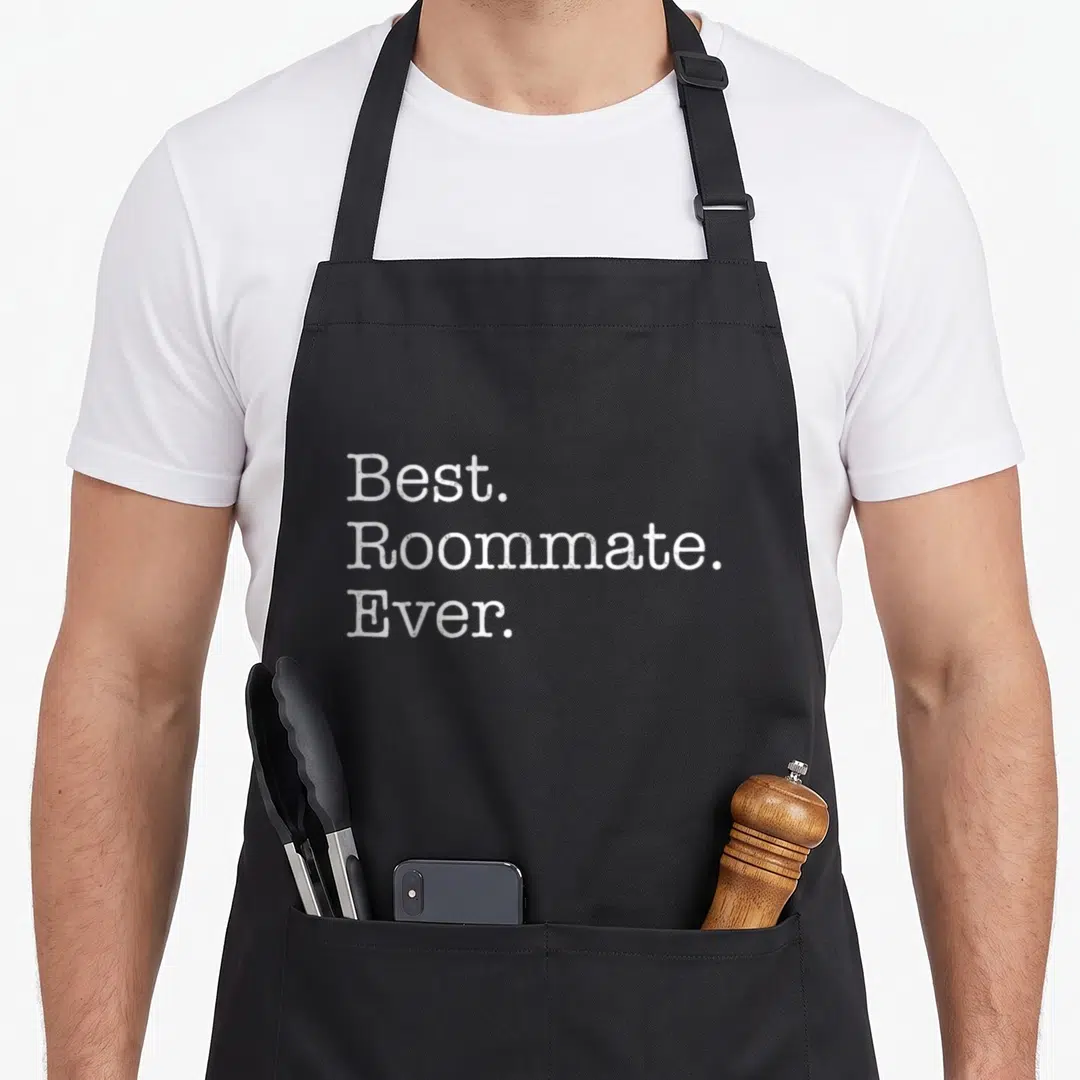 Roommate apron for men - White distressed text reading Best Roommate Ever stacked in three lines — shown on a black cotton canvas apron against a white background