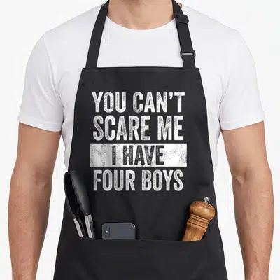 Scare four dad and son aprons - White distressed text YOU CAN'T SCARE ME I HAVE FOUR BOYS stacked on black fabric — shown on a black cotton canvas apron against a white background