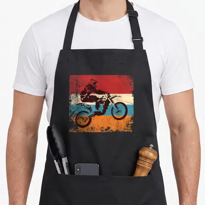 Motorcycle road apron - Black motocross rider silhouette over red orange blue and cream horizontal stripes — shown on a black cotton canvas apron against a white background