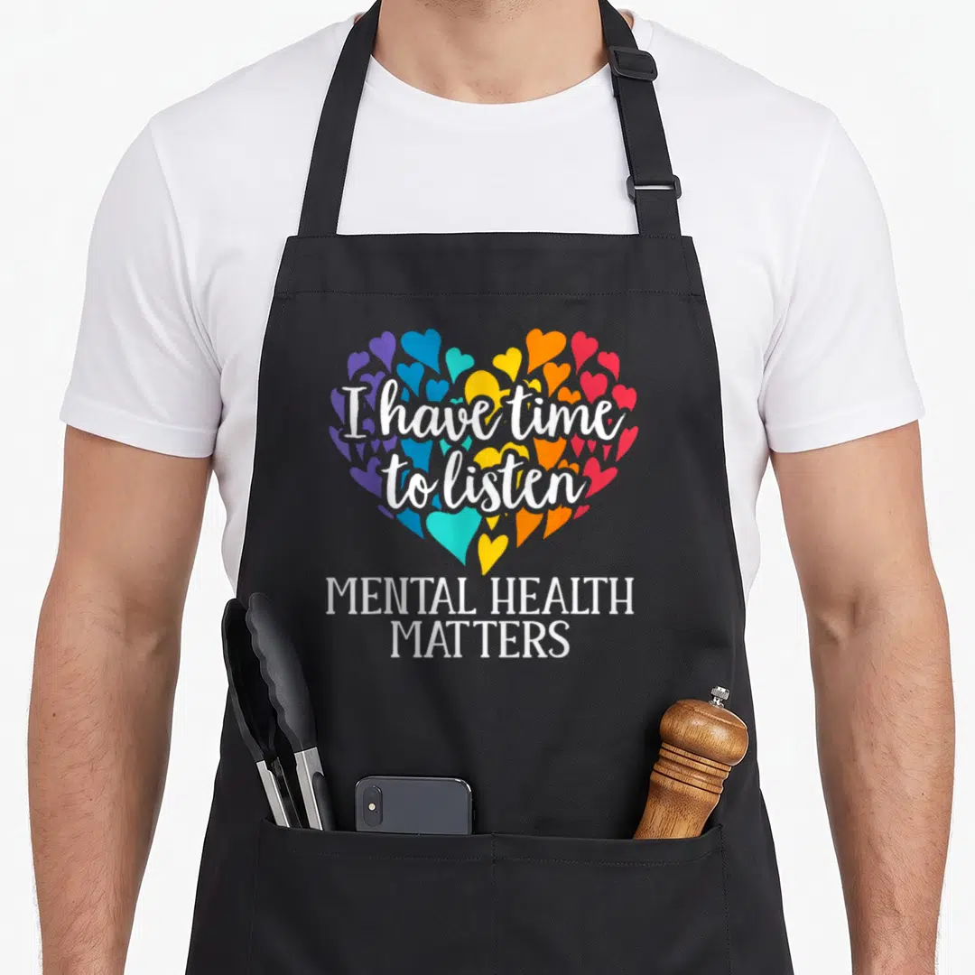 Listen depression awareness apron - Colorful heart mosaic with white text I have time to listen and Mental Health — shown on a black cotton canvas apron against a white background