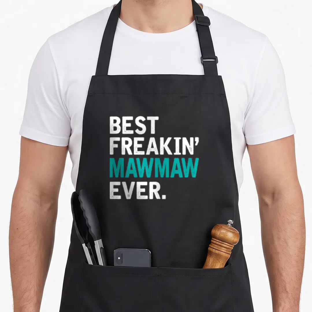 Freaking figure mom apron - White and teal stacked text reading Best Freakin Mawmaw Ever on black background — shown on a black cotton canvas apron against a white background
